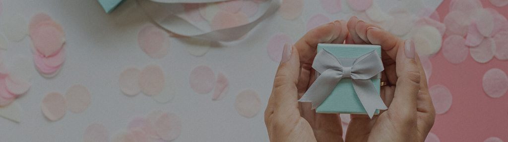 woman holding jewelry box with both hands with flower petals in the background